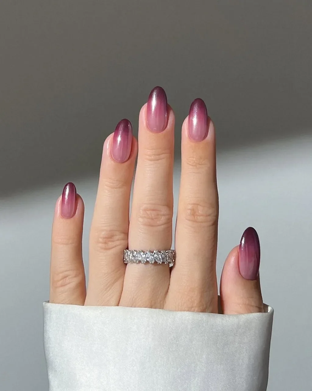 Ảnh cận cảnh móng tay đẹp với hiệu ứng ombre tím hồng quyến rũ và chiếc nhẫn kim cương sang trọng.